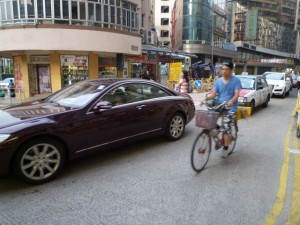 單車經過正在擠塞中的汽車龍；路上是太多單車還是太多汽車？（攝於九龍金巴利道）